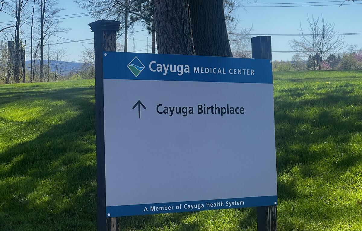 Sign for Cayuga Medical Center with an arrow pointing up labeled 'Cayuga Birthplace' on a grassy lawn