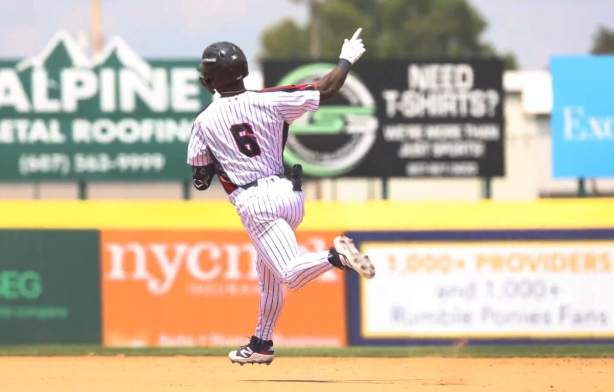 Back view of a baseball player in a white pinstriped uniform running on the dirt infield, number 6 visible on jersey, during a game.