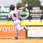 Back view of a baseball player in a white pinstriped uniform running on the dirt infield, number 6 visible on jersey, during a game.