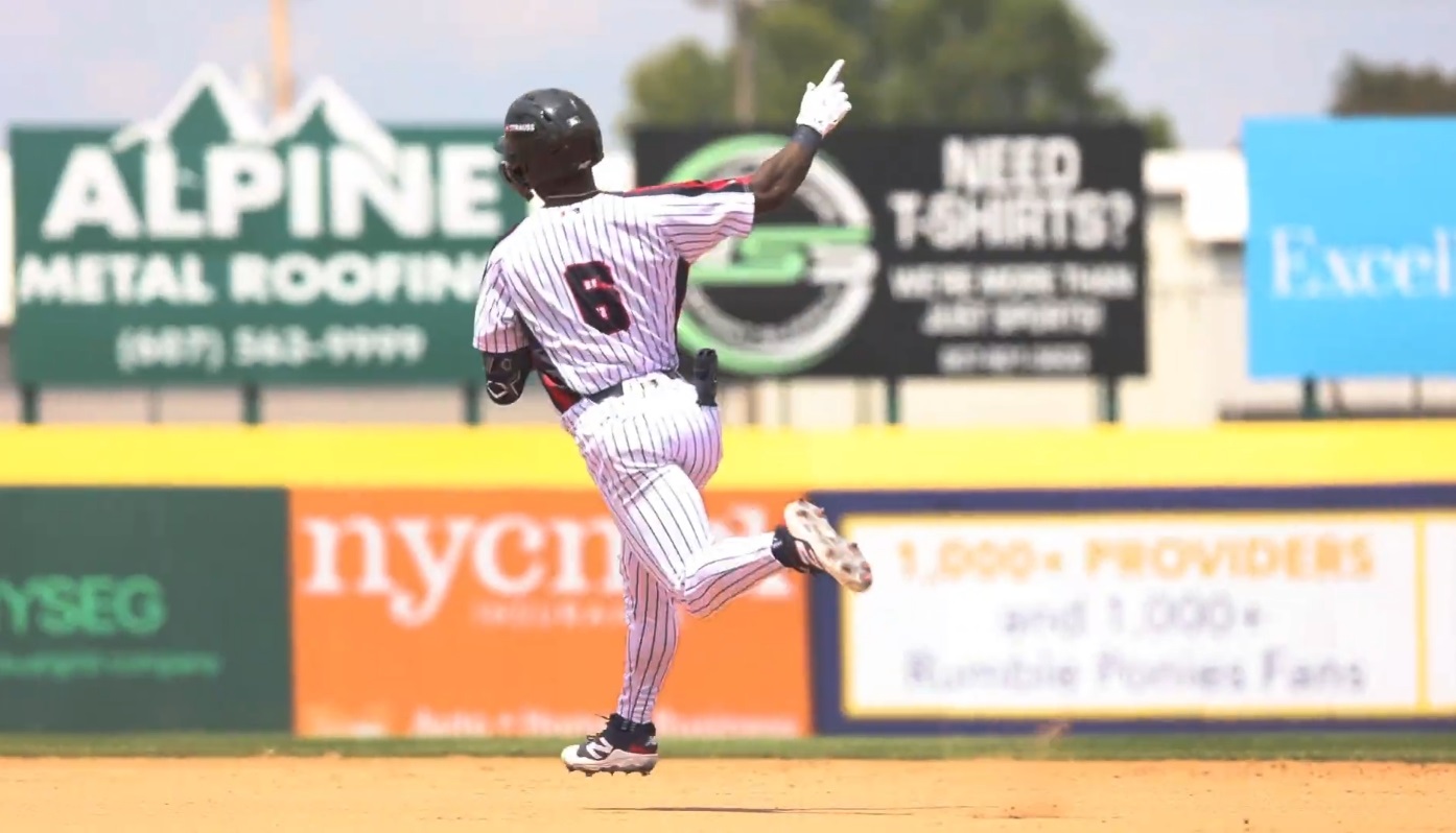 Back view of a baseball player in a white pinstriped uniform running on the dirt infield, number 6 visible on jersey, during a game.