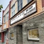 Cortland Bike Shop storefront with a large white sign reading 'CORTLAND BIKE SHOP SALES & SERVICE' over a stone facade.