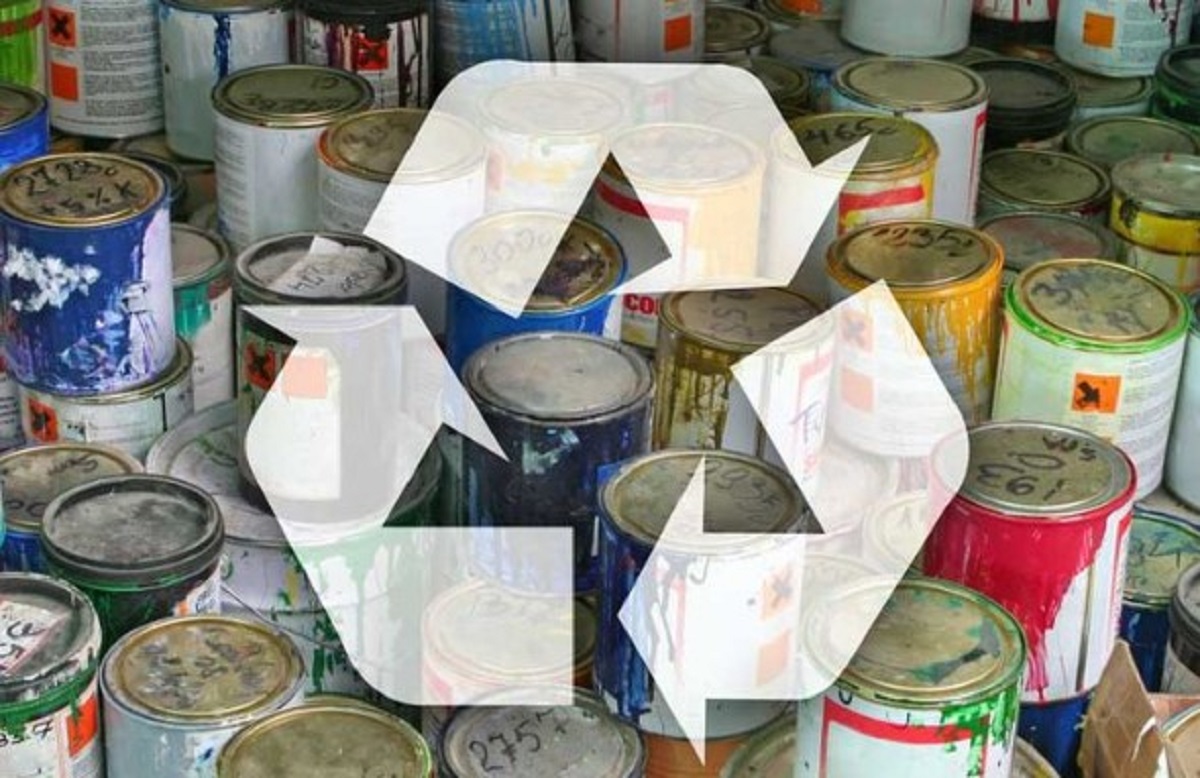 Paint cans piled together with a large translucent recycling symbol overlaid, signaling paint recycling.