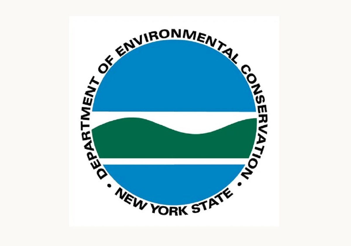 Circular logo for the New York State Department of Environmental Conservation (DEC). It shows blue sky and water with green hills, surrounded by the department name in a ring.