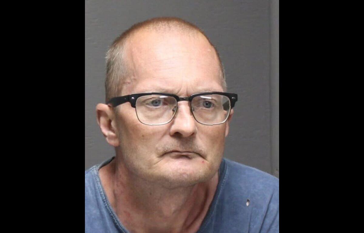 Mugshot of a middle-aged man with glasses, wearing a blue shirt, looking slightly to the left with a neutral expression.