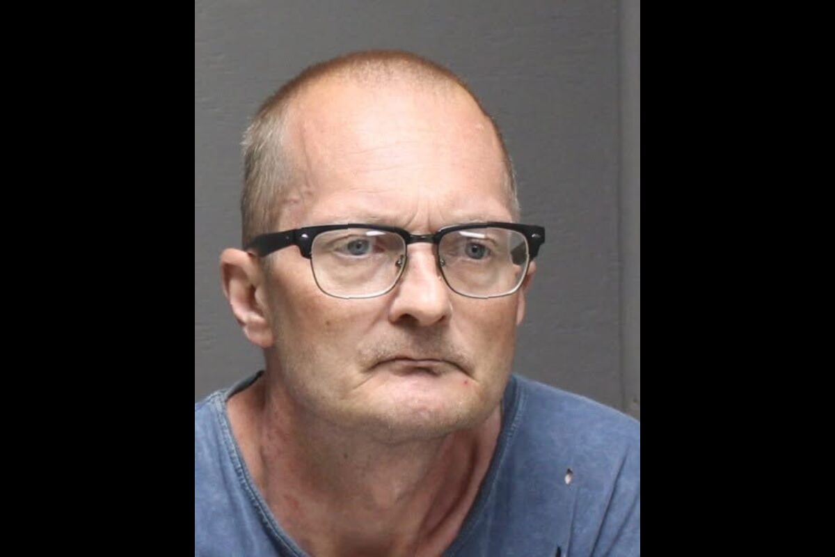 Mugshot of a middle-aged man with glasses, wearing a blue shirt, looking slightly to the left with a neutral expression.