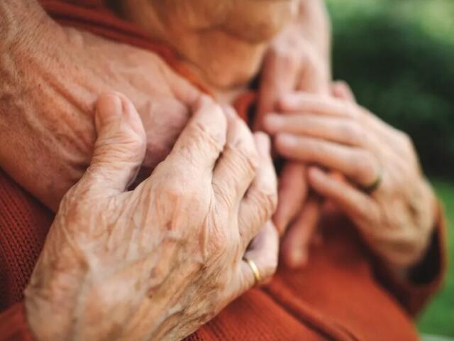 Elderly person's hands over younger person's hands