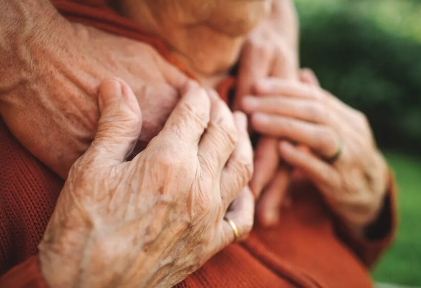 Elderly person's hands over younger person's hands