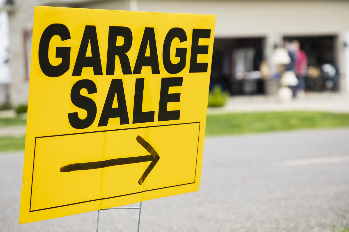 Bright yellow garage sale sign with bold black text and a right-pointing arrow