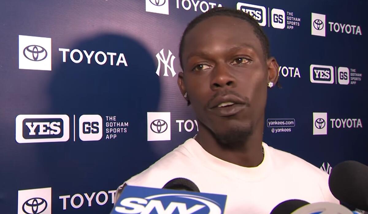 Athlete being interviewed at a press backdrop with Yankees and Toyota logos; several microphones in front.
