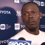 Athlete being interviewed at a press backdrop with Yankees and Toyota logos; several microphones in front.