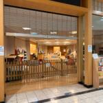 Store interior with a wooden fence and open space, shelves and a sign announcing Nook grand reopening.